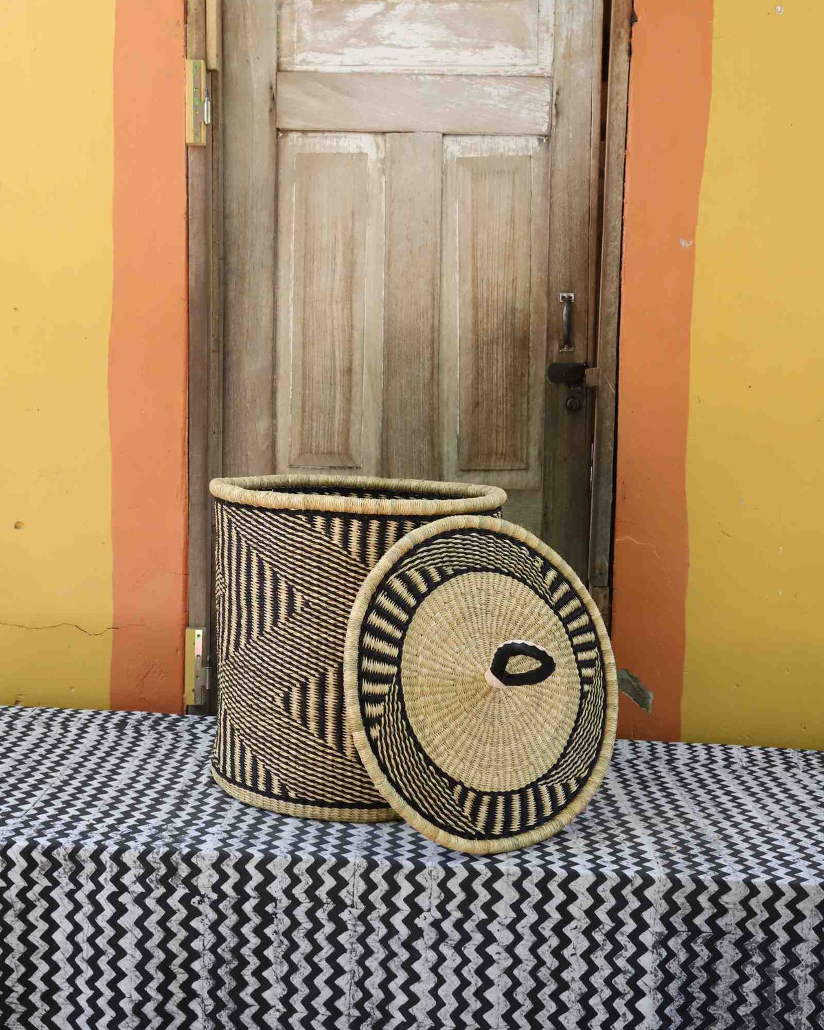Handwoven Bolga laundry basket with lid removed, natural body with dark wave stripes and natural lid.