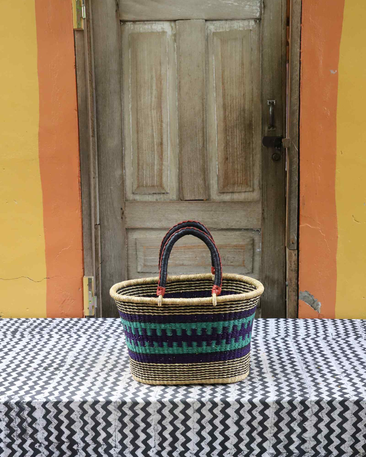 Medium handwoven Bolga Zaane Tia market basket in natural straw with teal, red and black fine banded stripes.