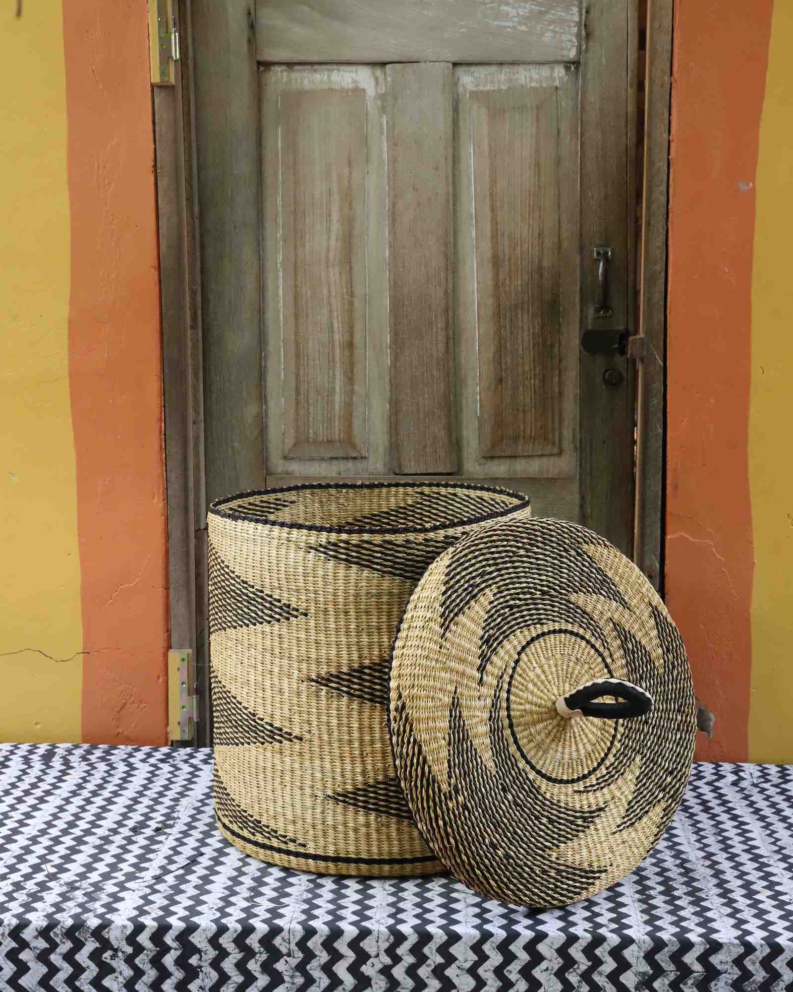 Handwoven Bolga laundry basket with lid shown removed, showing a natural-straw interior and zigzag exterior.