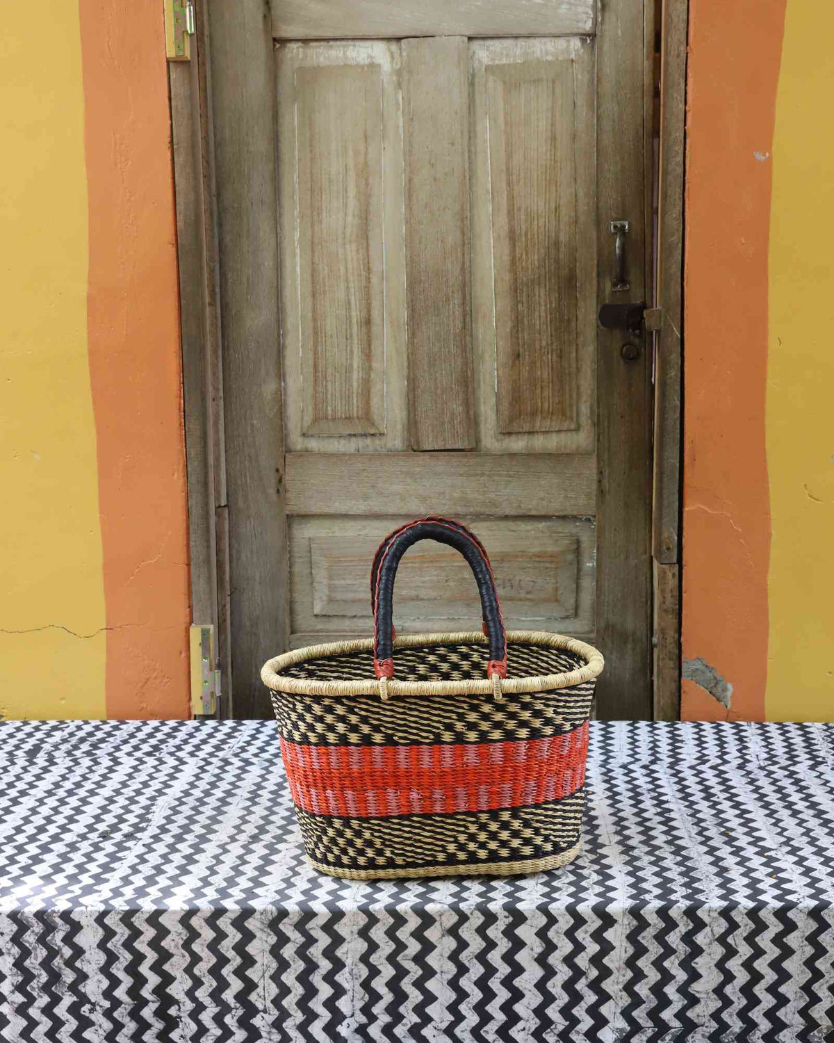Medium handwoven Bolga Zaane Tia market basket in natural straw with a red and orange banded accent.