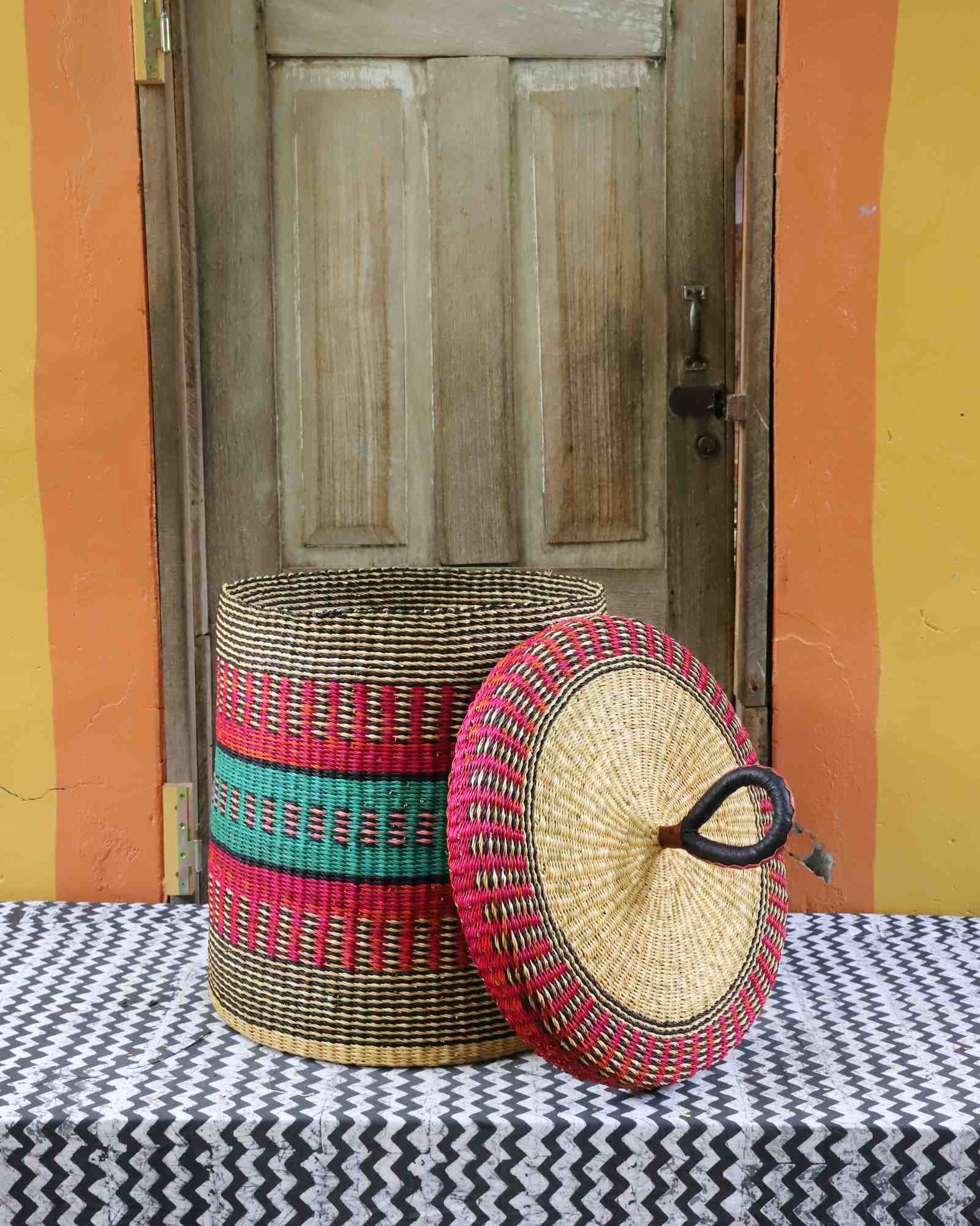 Handwoven Bolga laundry basket with lid removed, showing red and green banded body and natural woven lid.