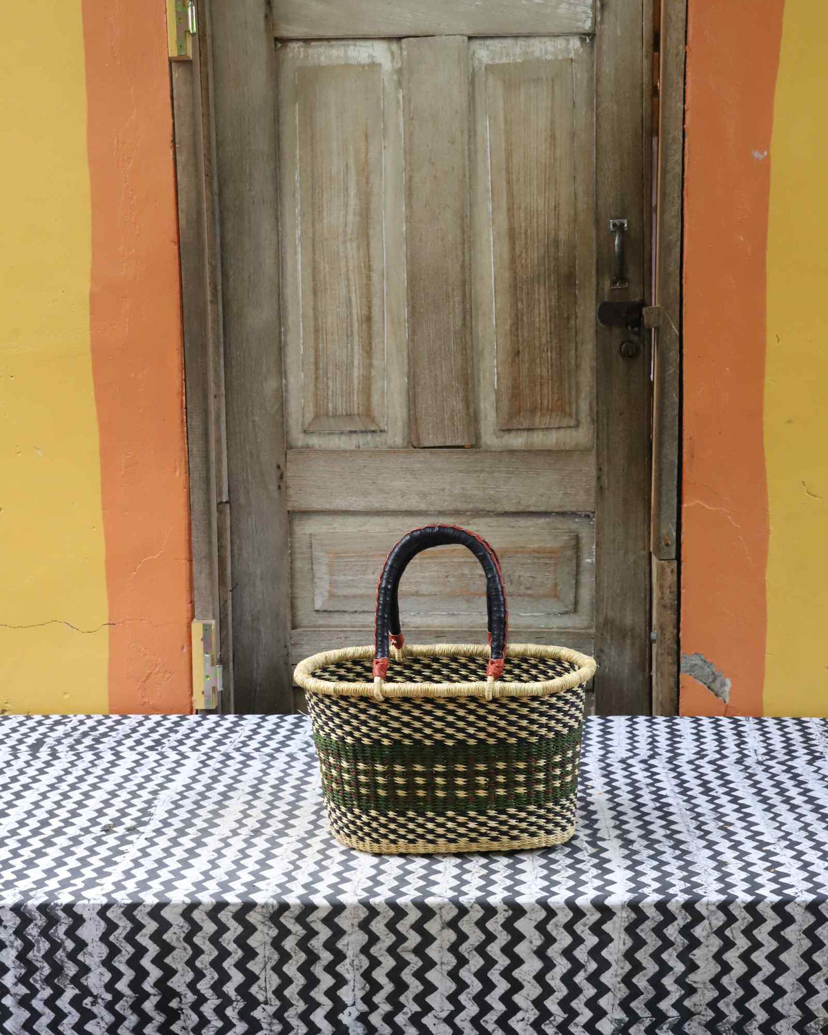 Small handwoven Bolga Zaane Tia market basket in natural straw with a dark and orange zigzag weave band.