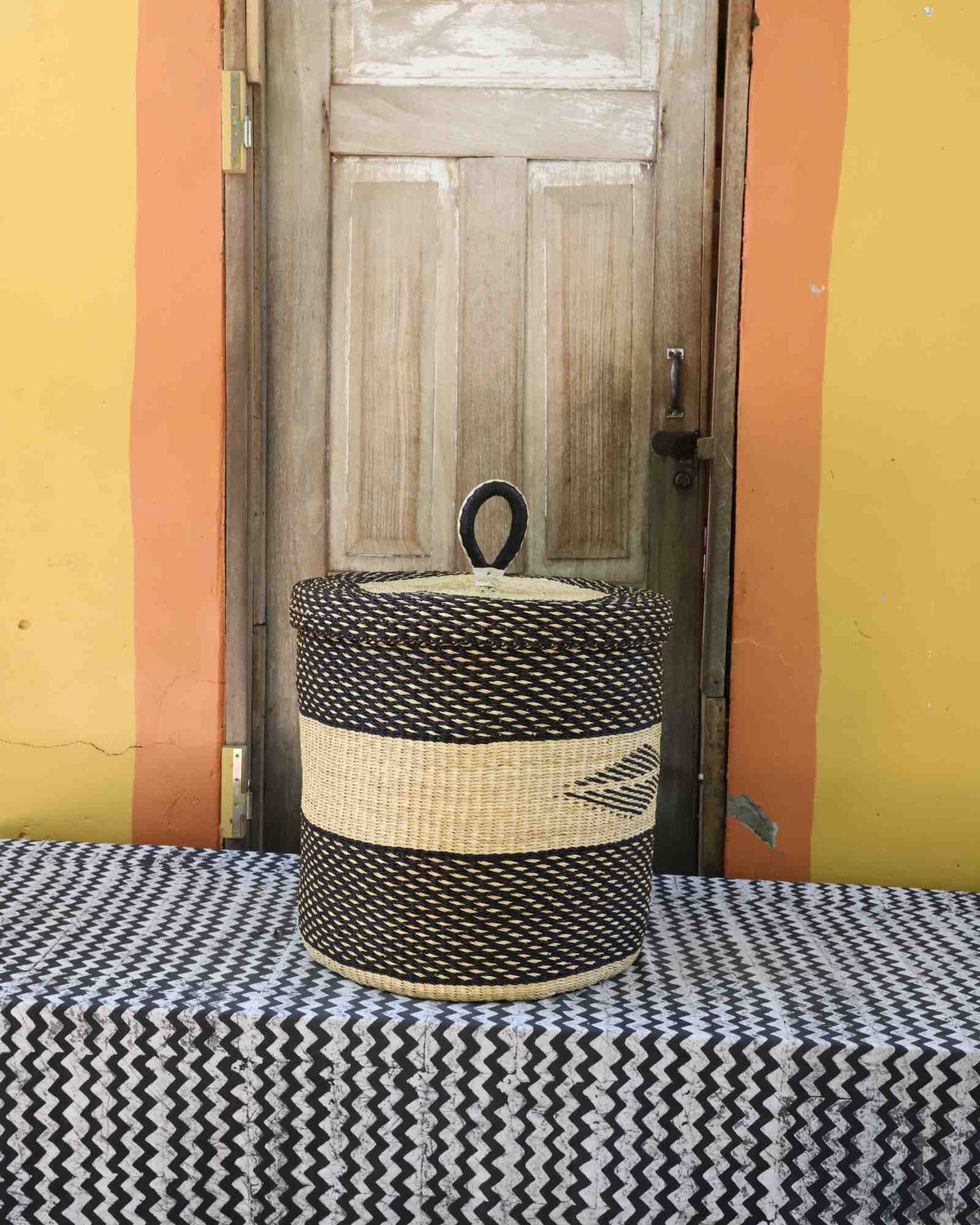 Handwoven Bolga laundry basket with lid in dark elephant grass with a natural straw central band.