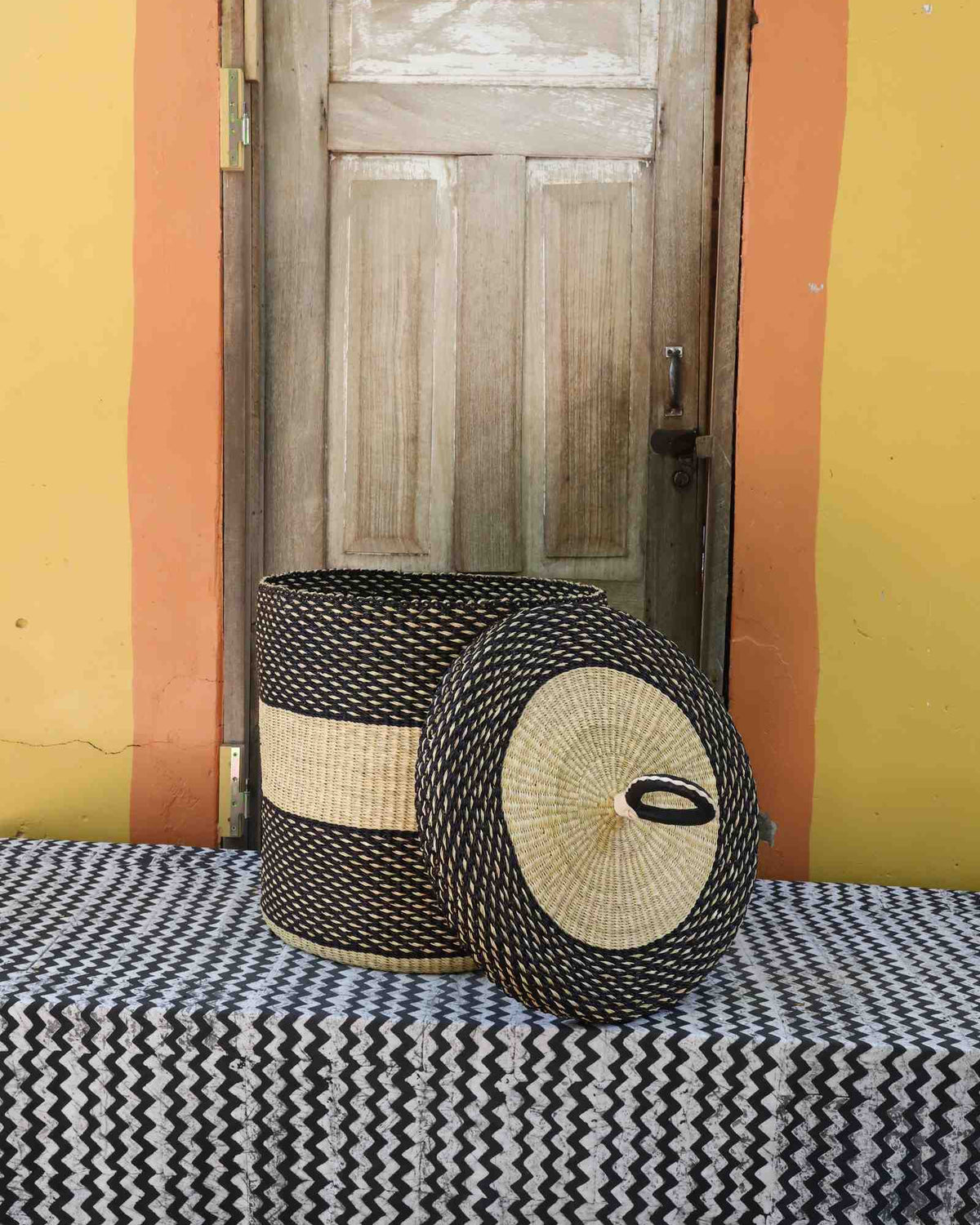 Handwoven Bolga laundry basket with lid removed, dark body with natural central band and matching lid.
