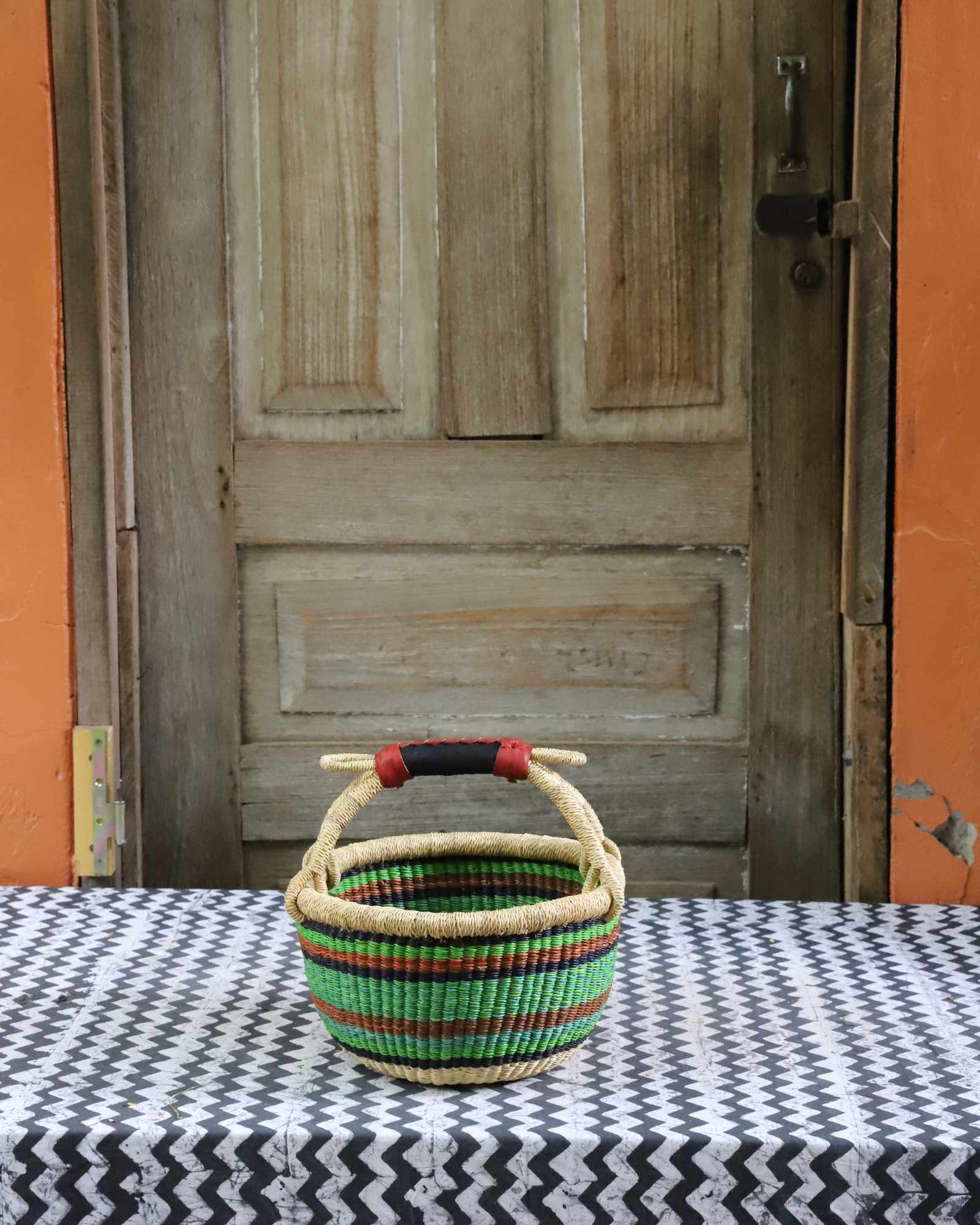 Round Bolga basket handwoven in elephant grass, with a tight weave and twin handles.
