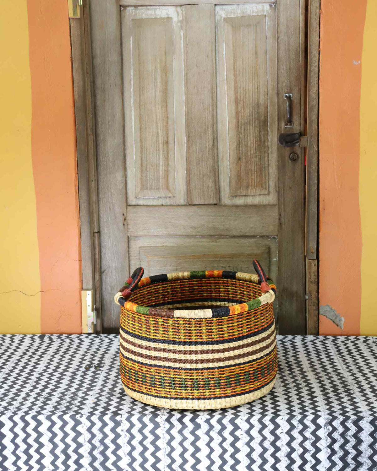 Small handwoven Bolga storage tub in natural straw with fine red banded stripes.