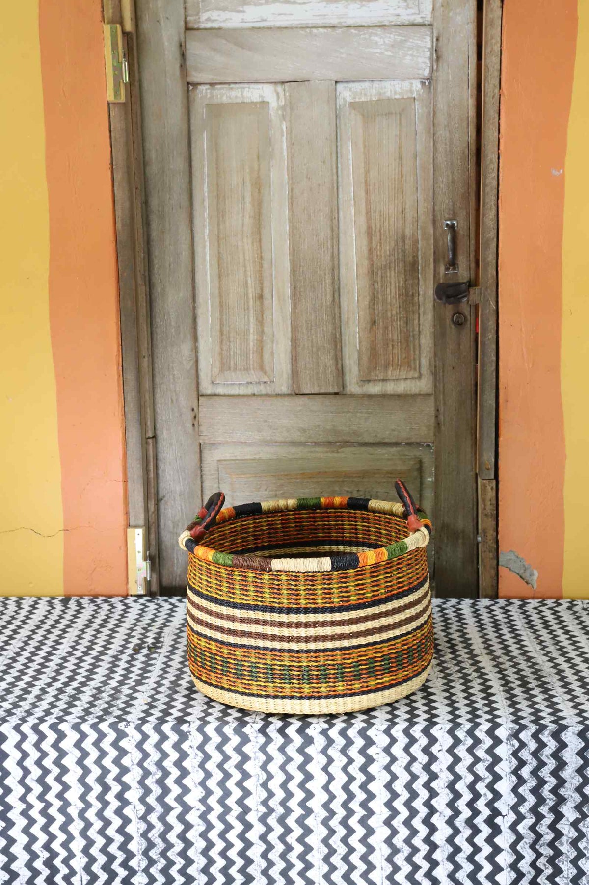 Small handwoven Bolga storage tub in natural straw with fine red banded stripes.