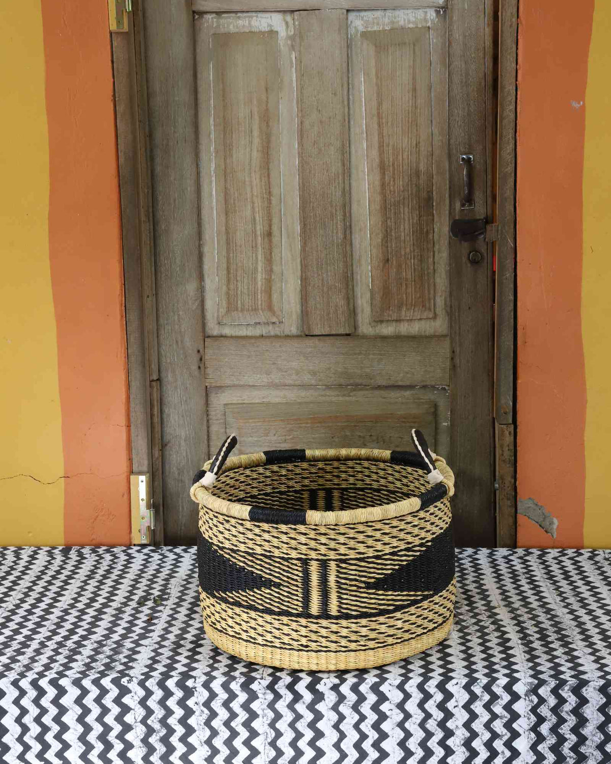Small handwoven Bolga storage tub in dyed black with fine natural stripes and leather-wrapped handles.