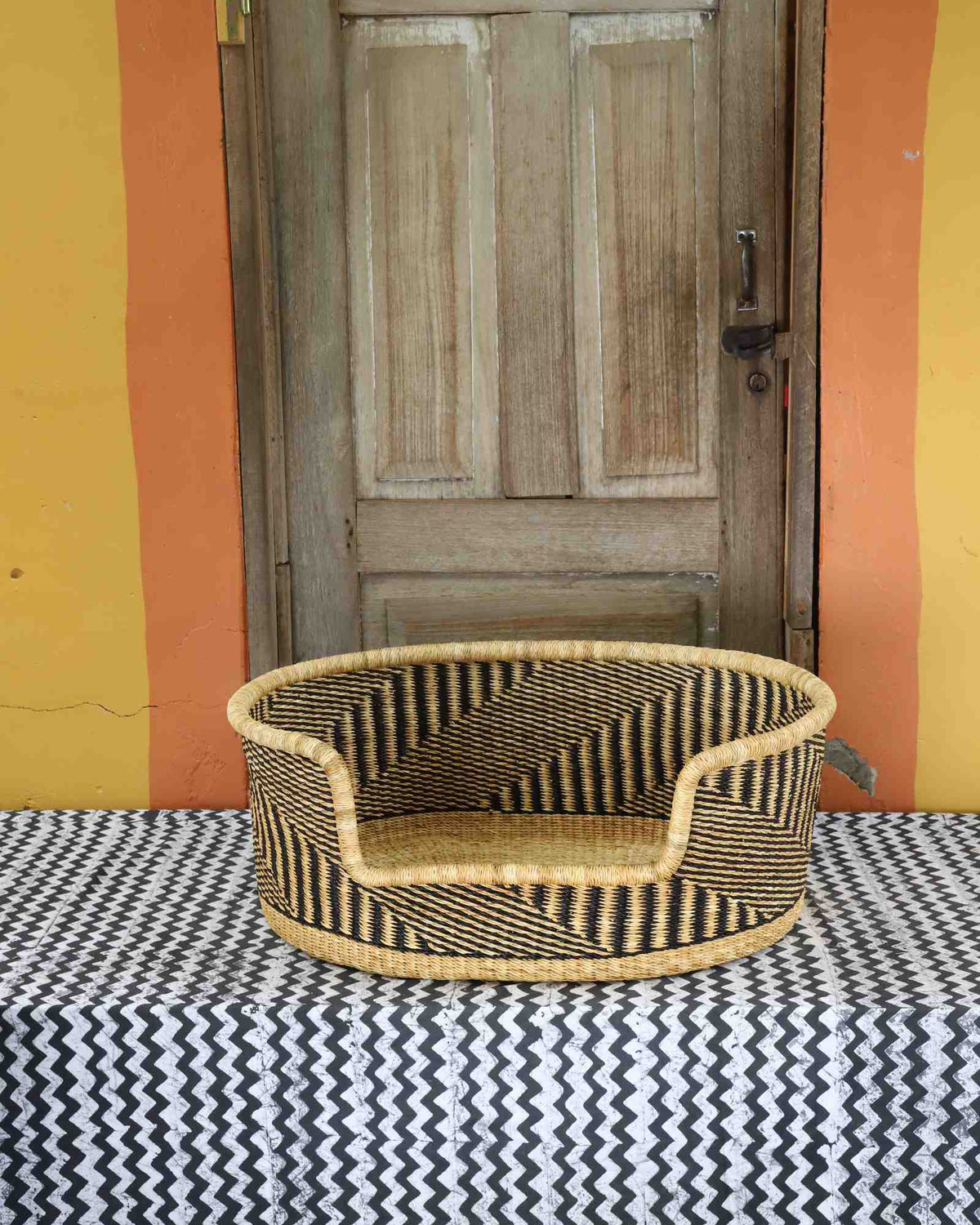 Medium handwoven Bolga pet bed in natural straw with a fine black herringbone weave pattern.