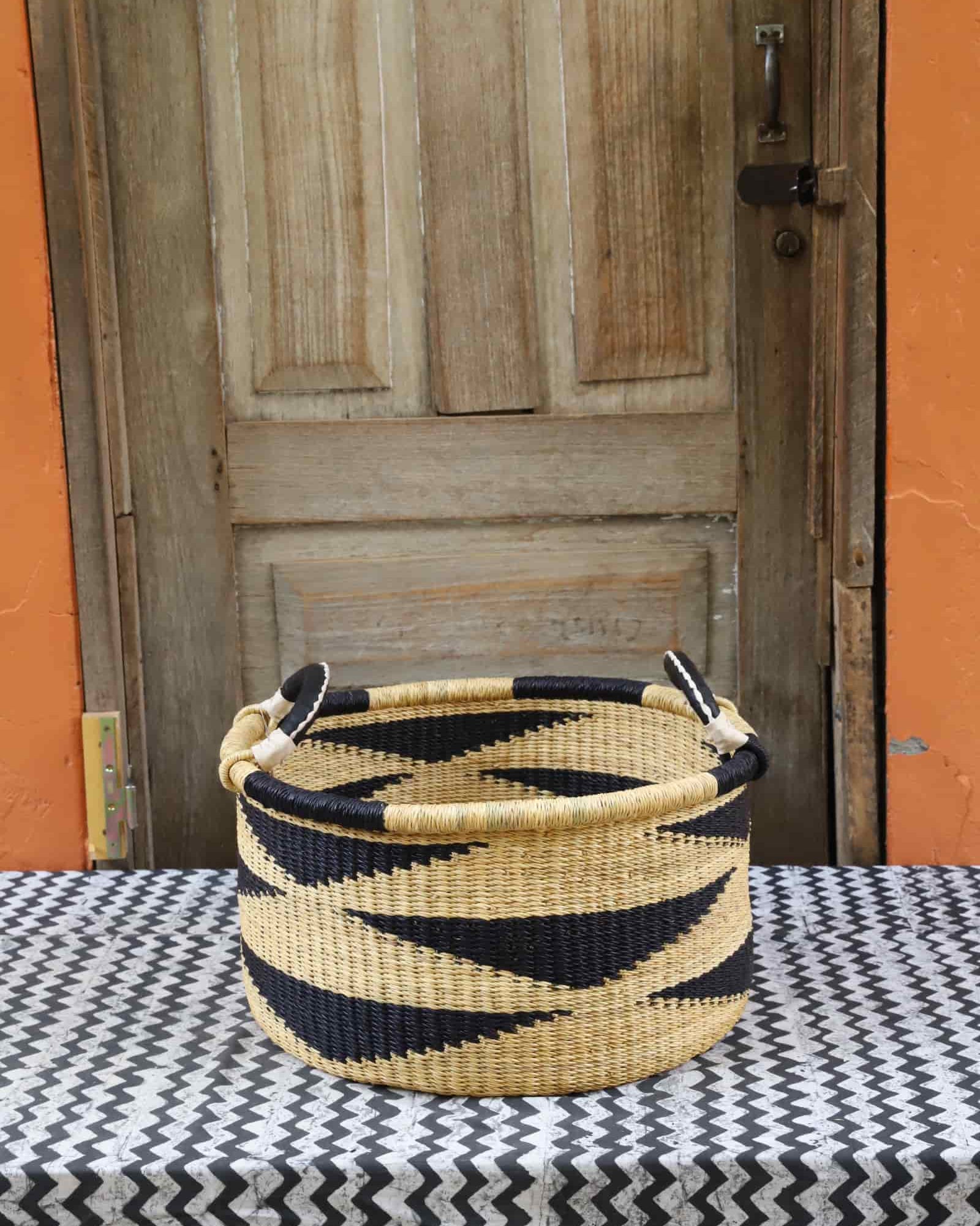 Woven Tub (Small) handwoven in Ghana sitting on black and white cloth with wooden door background