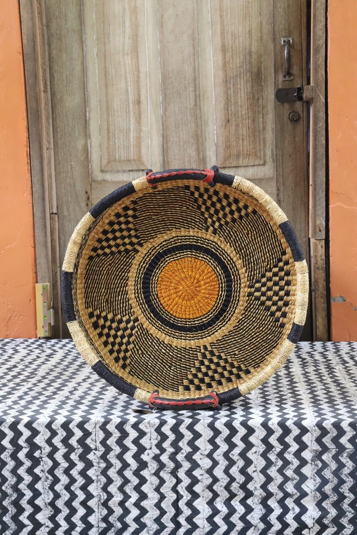 Woven basket on a table with black and white cloth a wooden door in the background