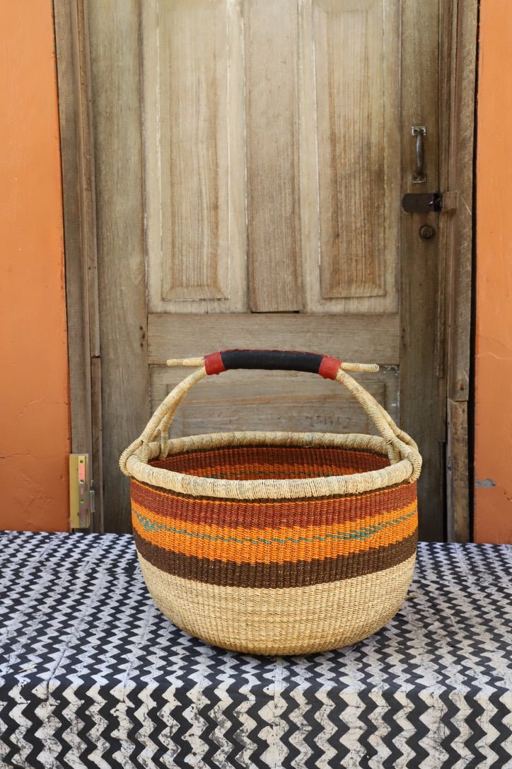 Woven carry on bag with premium leather handles on a black and white cloth against a wooden door.