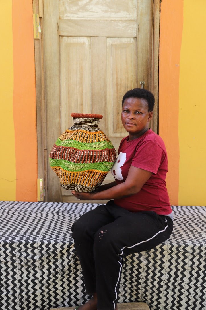 Woman holding a colorful woven piece on a black and white cloth against a wooden door