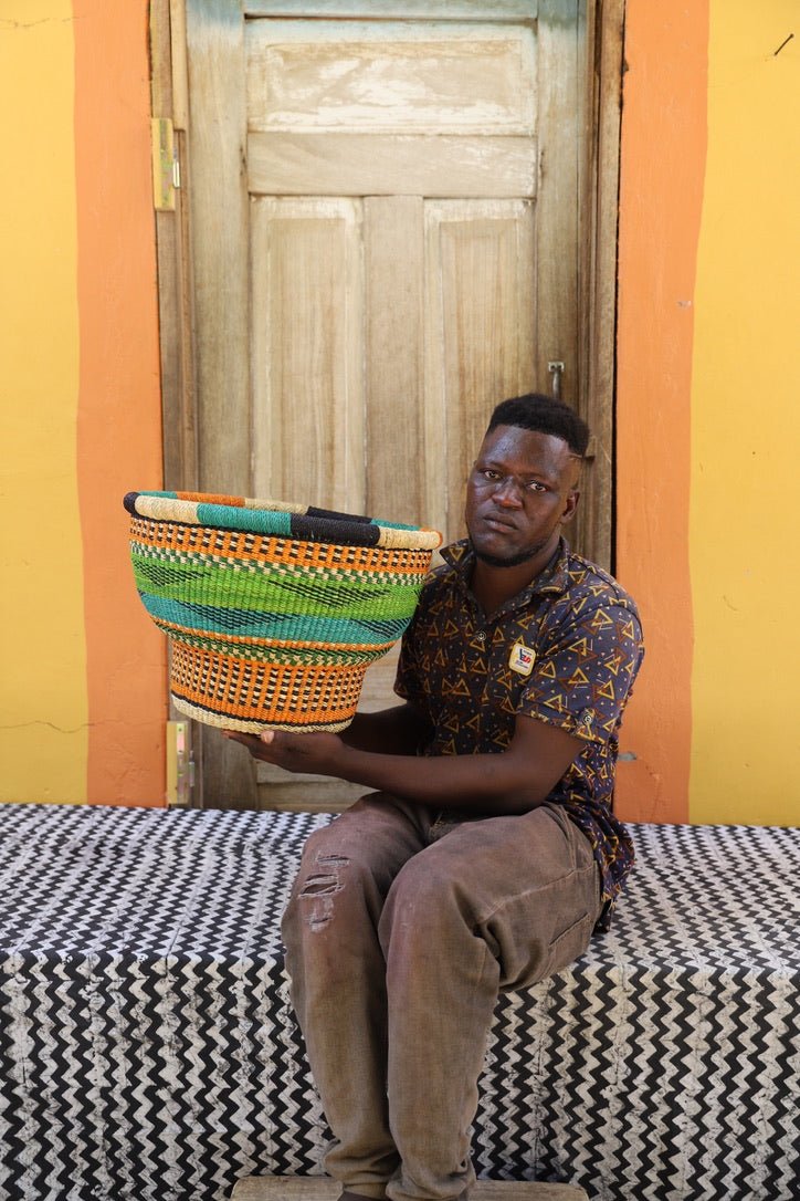 Person holding a colorful woven basket against a vibrant wall.