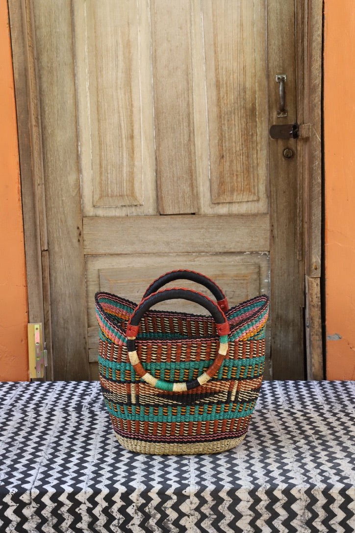 Woven carry on basket with premium leather on a black and white cloth against a wooden door