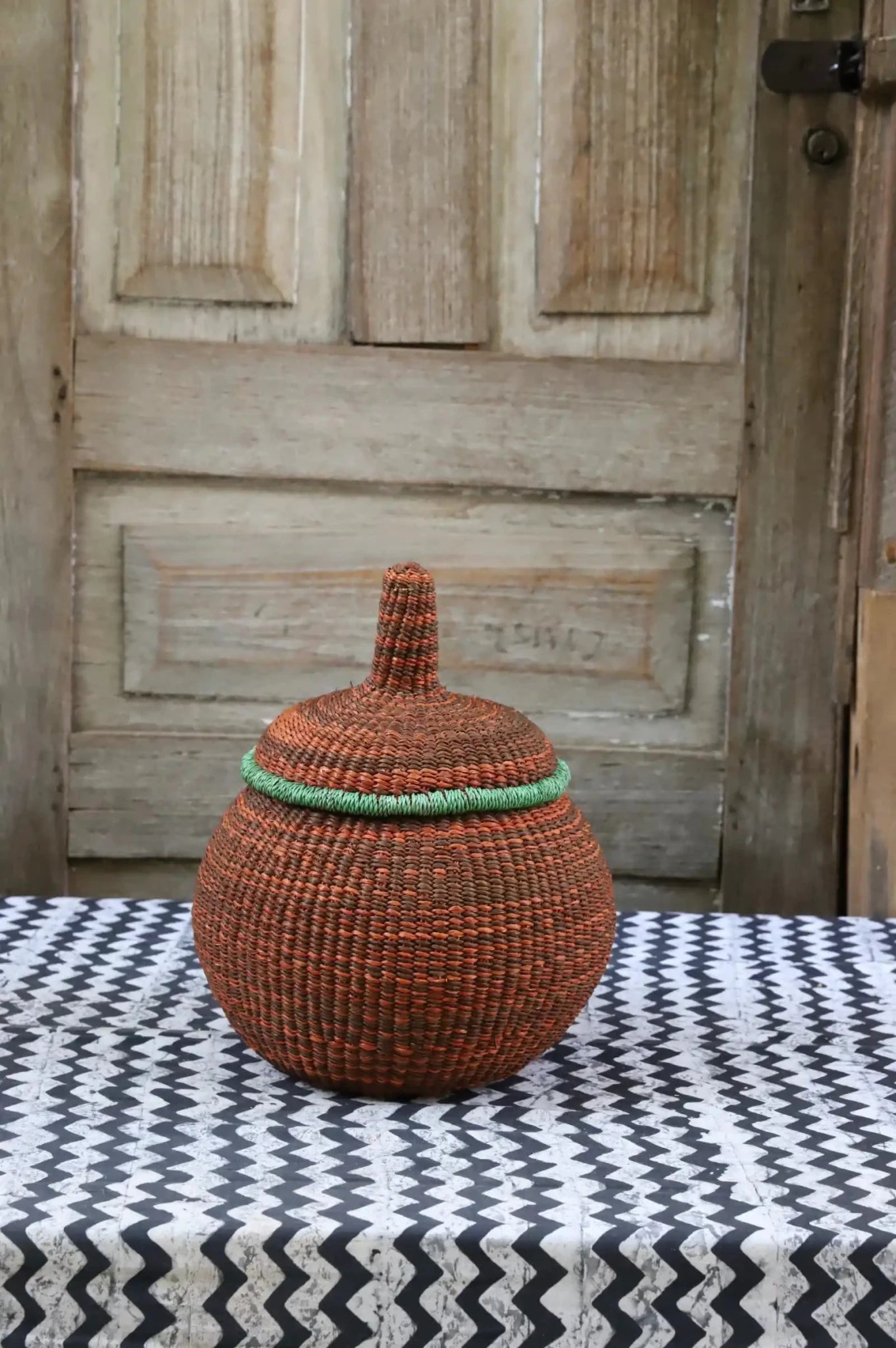 Woven storage basket with colorful patterns on a black and white cloth against a wooden door