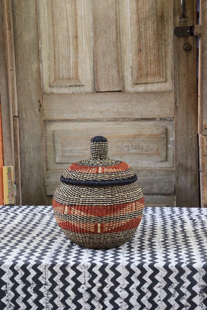 Woven storage basket with colorful patterns on a black and white cloth against a wooden door