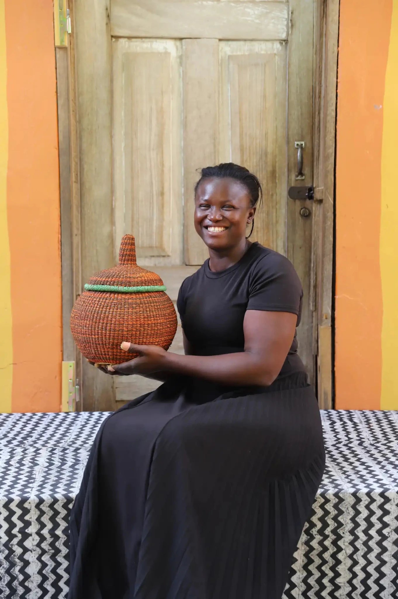 Woman holding small Orbit storage basket in dark rust with green rim band