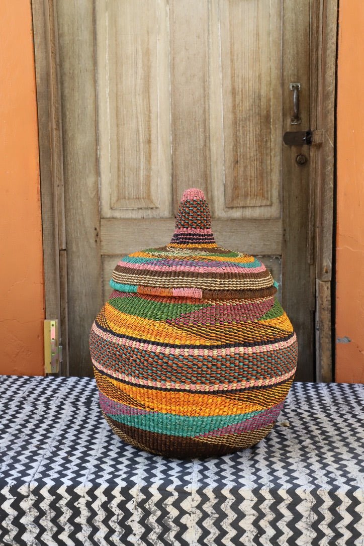 Woven storage basket with colorful patterns on a black and white cloth against a wooden door