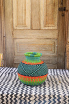 Colorful woven vase on a patterned surface with a wooden door in the background