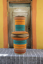 Colorful woven basket on a black and white patterned surface with a wooden door in the background.