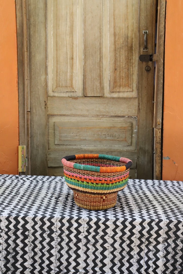 Woven storage basket with a beautiful pattern on a black and white cloth against a wooden door.