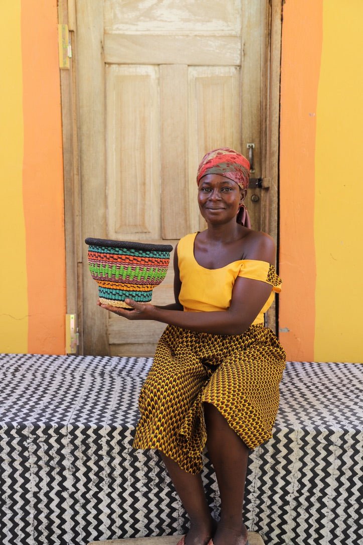 Woman holding a colorful basket in front of a wooden door with orange and yellow walls.