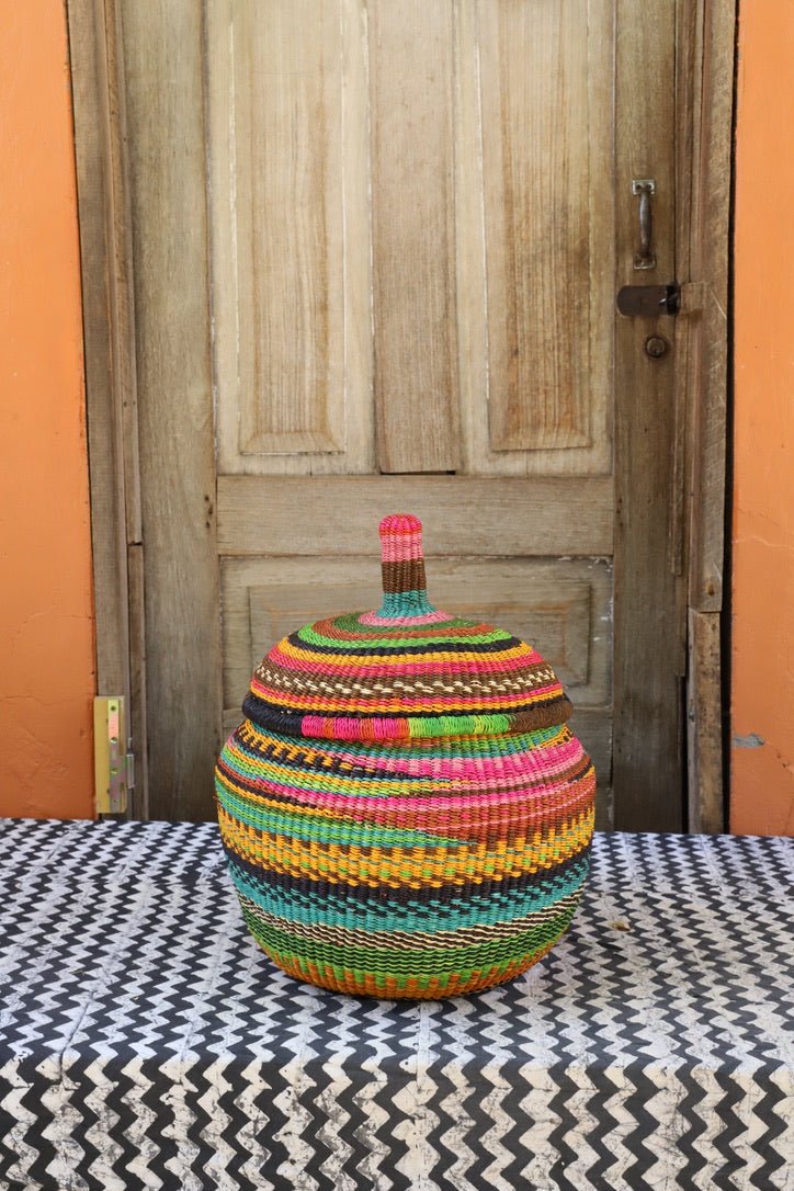 Woven storage basket with colorful patterns on a black and white cloth against a wooden door