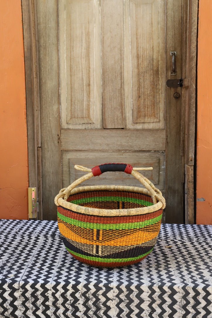 Woven carry on bag with premium leather handles on a black and white cloth against a wooden door.