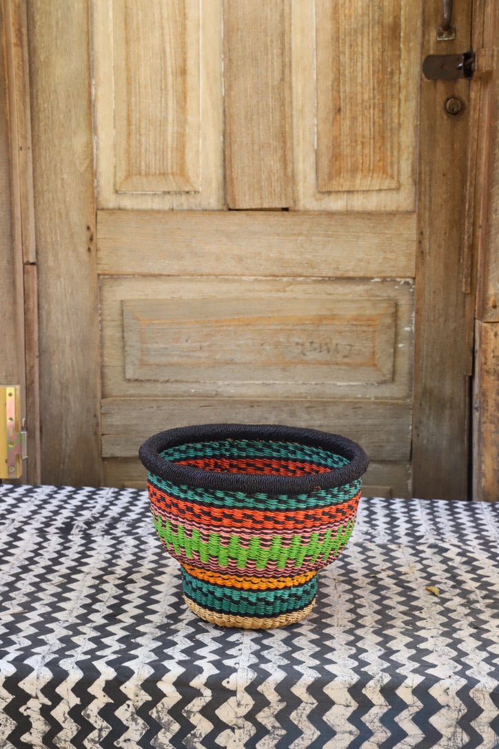 Colorful woven basket on a patterned surface with a wooden door in the background