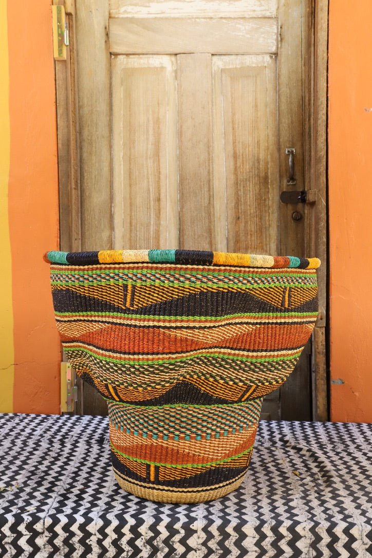 A colorful, handwoven piece sitting on a black and white cloth against a wooden door