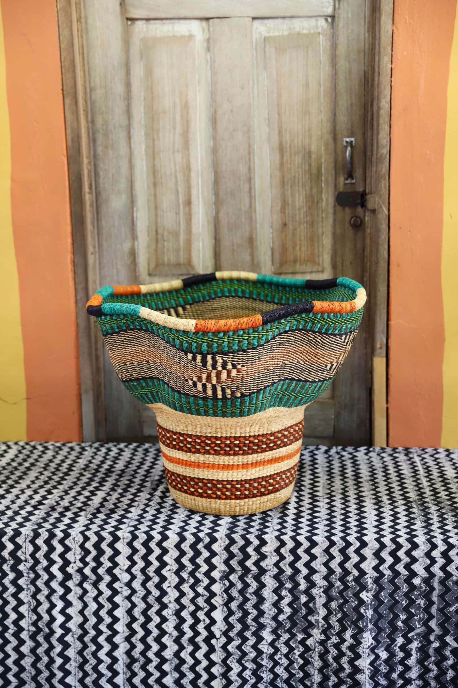 A colorful, handwoven piece sitting on a black and white cloth against a wooden door