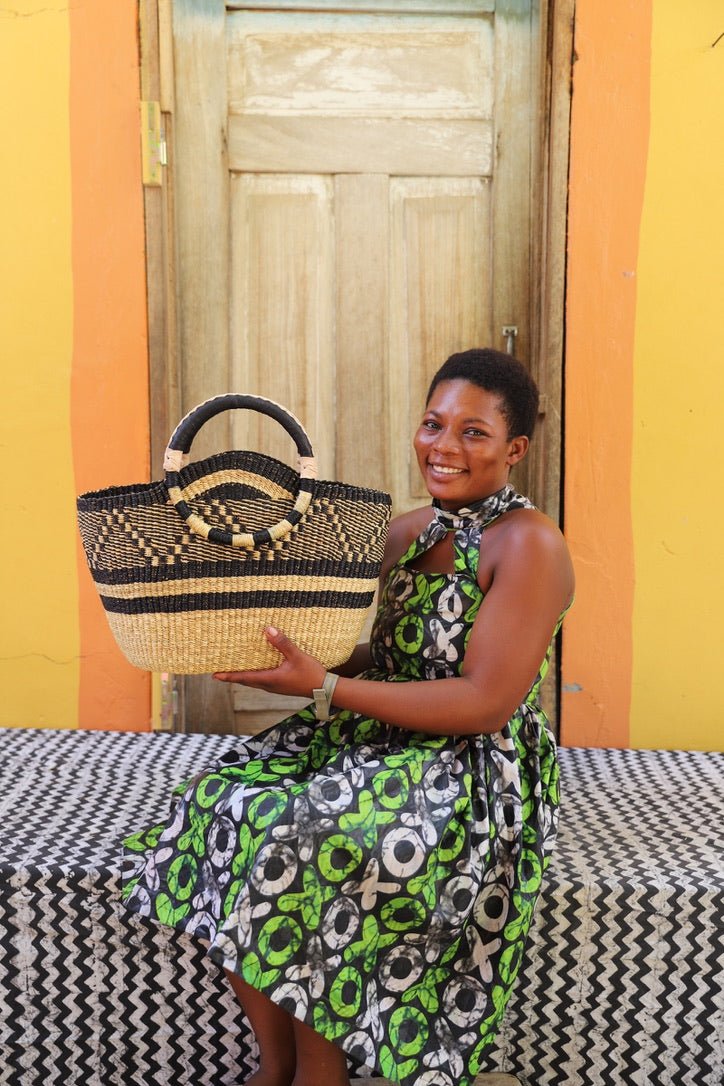 Artisan holding a colorful woven carry on bag with premium leather handles on a black and white cloth against a wooden door.