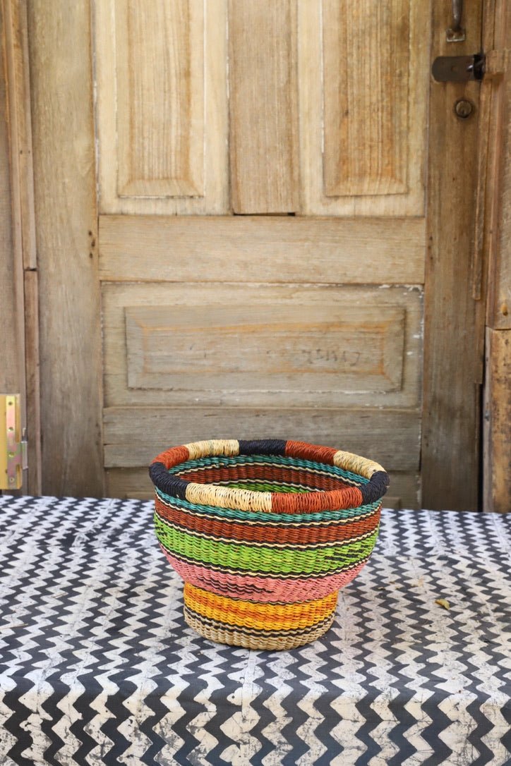 Colorful woven basket on a patterned surface with a wooden door in the background