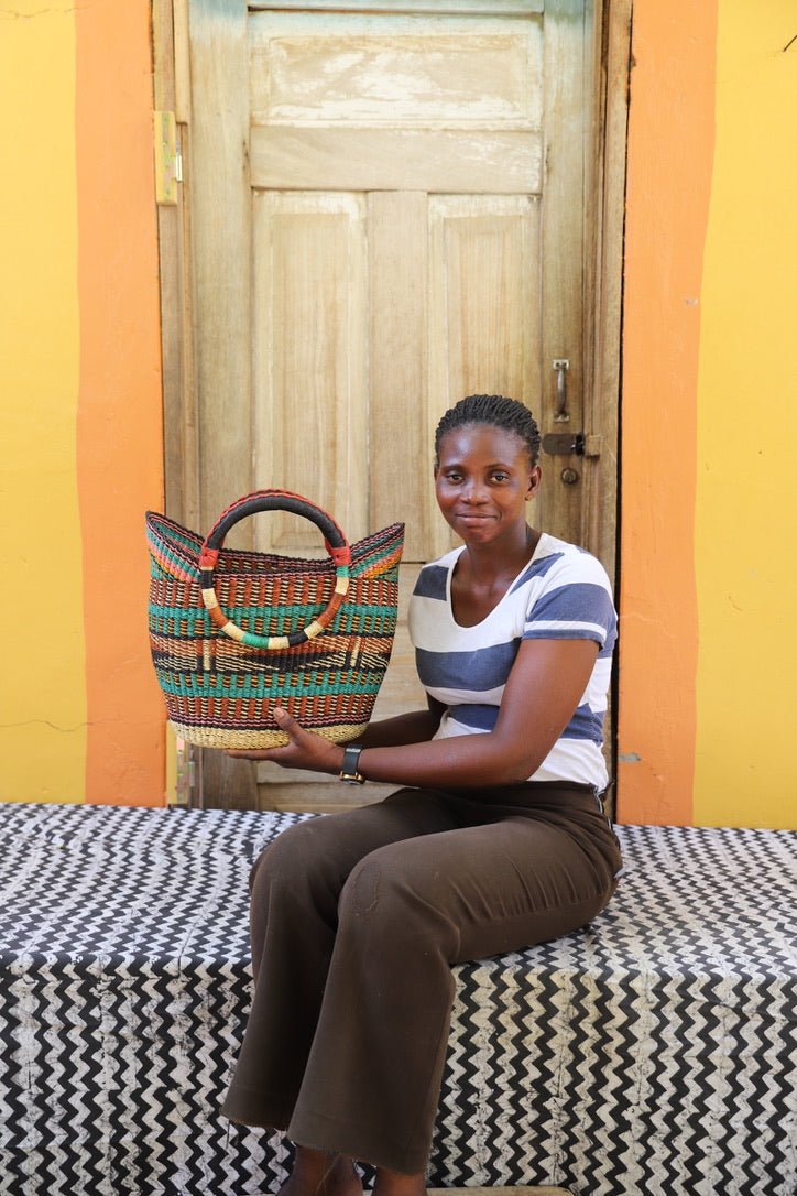 Woman holding a woven basket in front of a colorful wall.