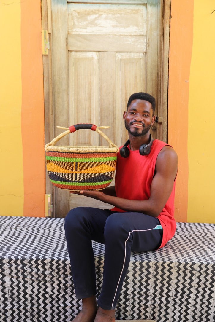 Man in red vest holding a large terracotta and orange diagonal-patterned Bolga shopping basket