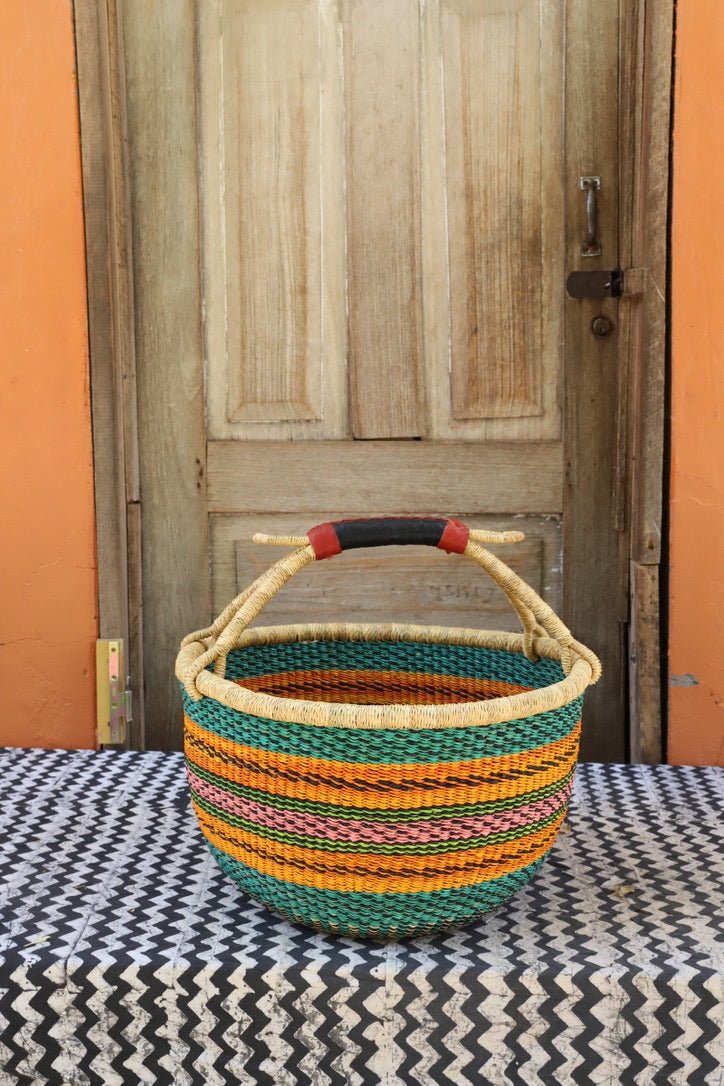 Woven carry on bag with premium leather handles on a black and white cloth against a wooden door.