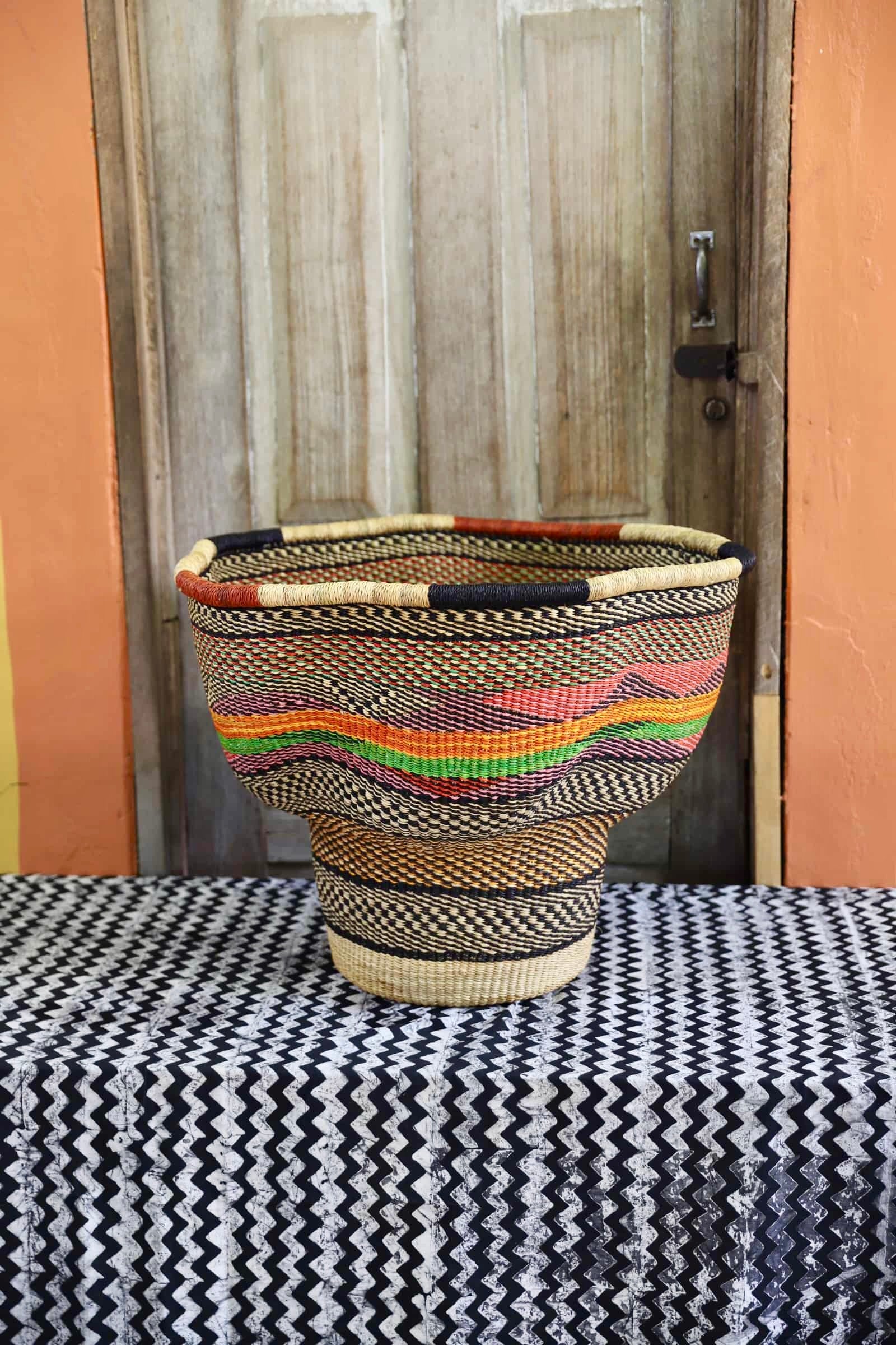 A patterned, handwoven piece sitting on a black and white cloth against a wooden door