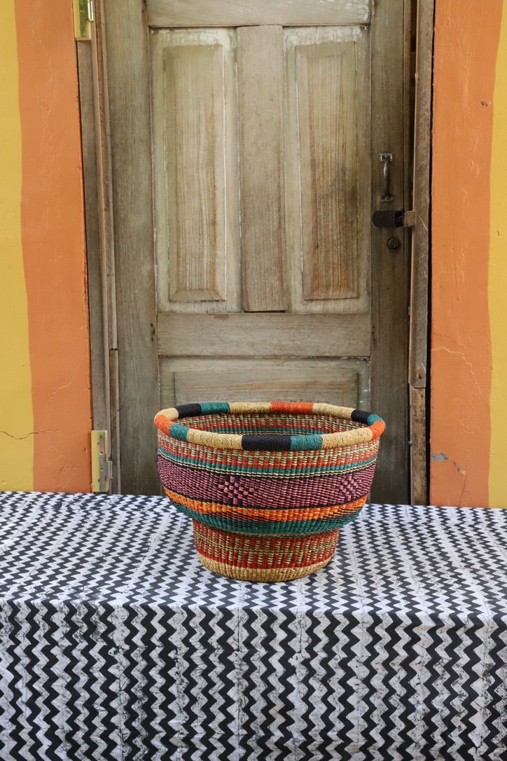 Colorful woven basket on a table with a wooden door and colorful wall in the background