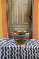 Colorful woven basket on a table with a wooden door and colorful wall in the background
