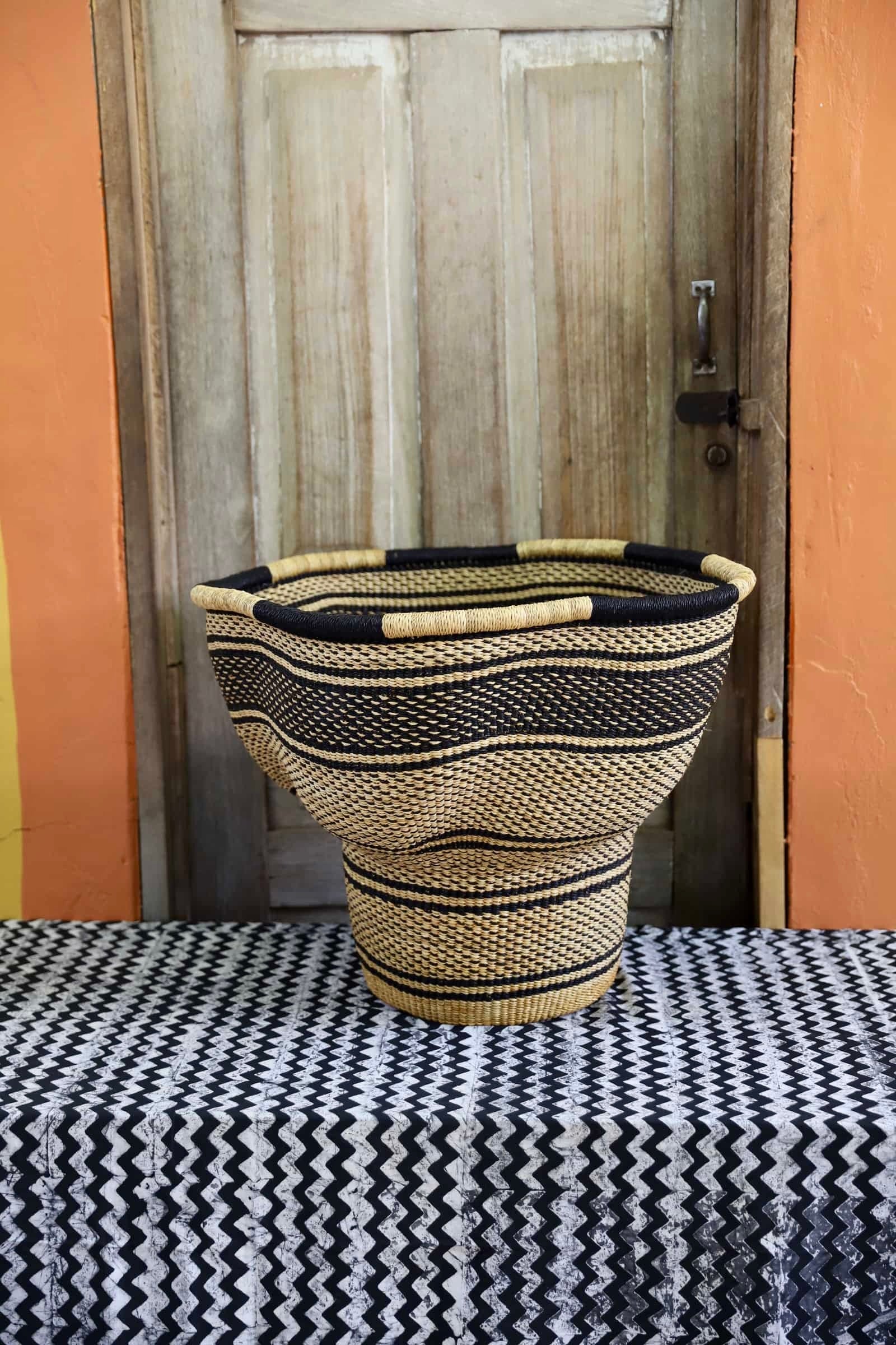 A patterned, handwoven piece sitting on a black and white cloth against a wooden door