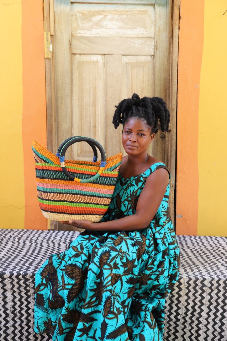 Woman holding a colorful striped bag against a yellow wall