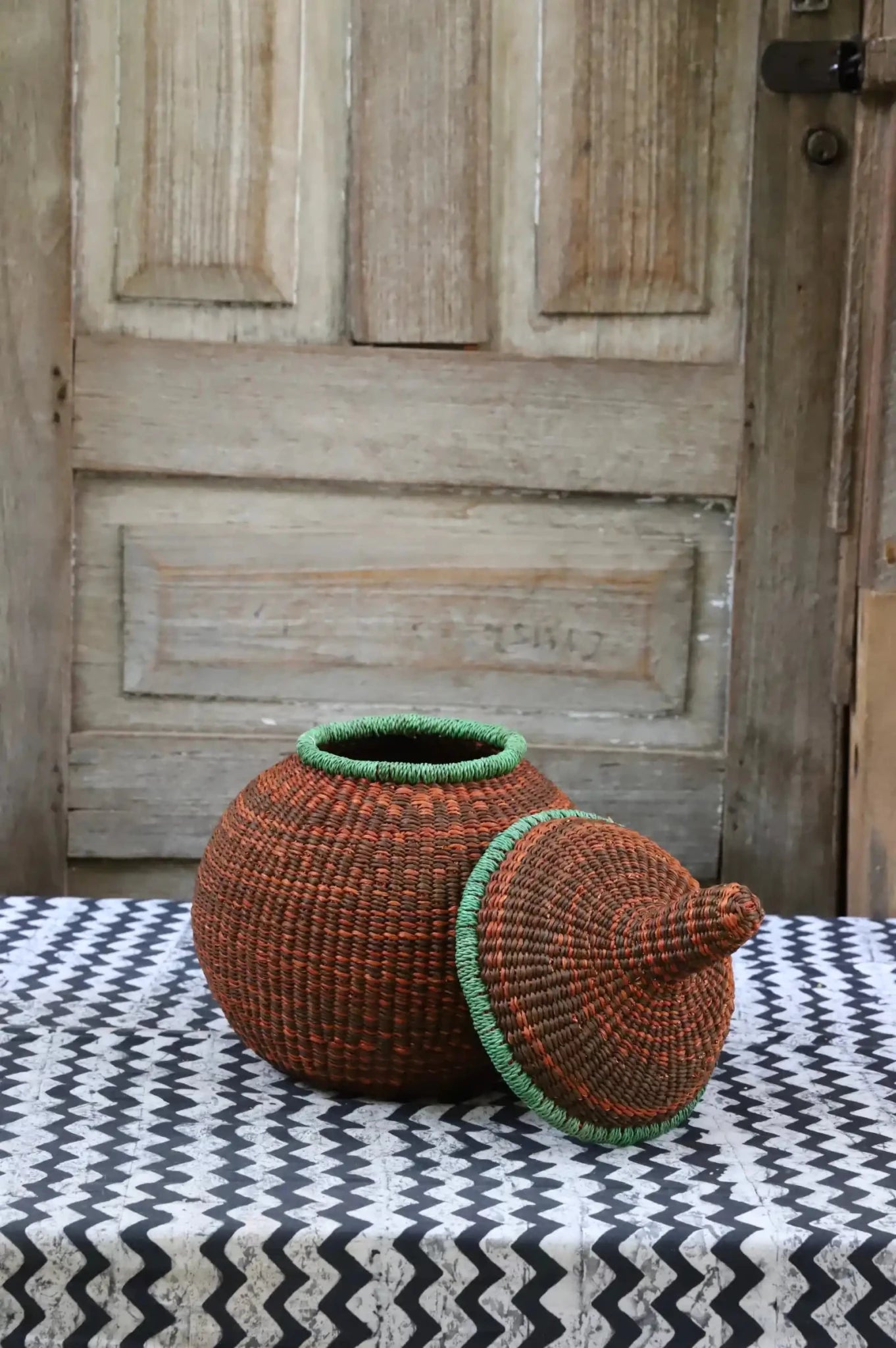 Small Orbit storage basket in dark rust with green trim, lid off showing round form