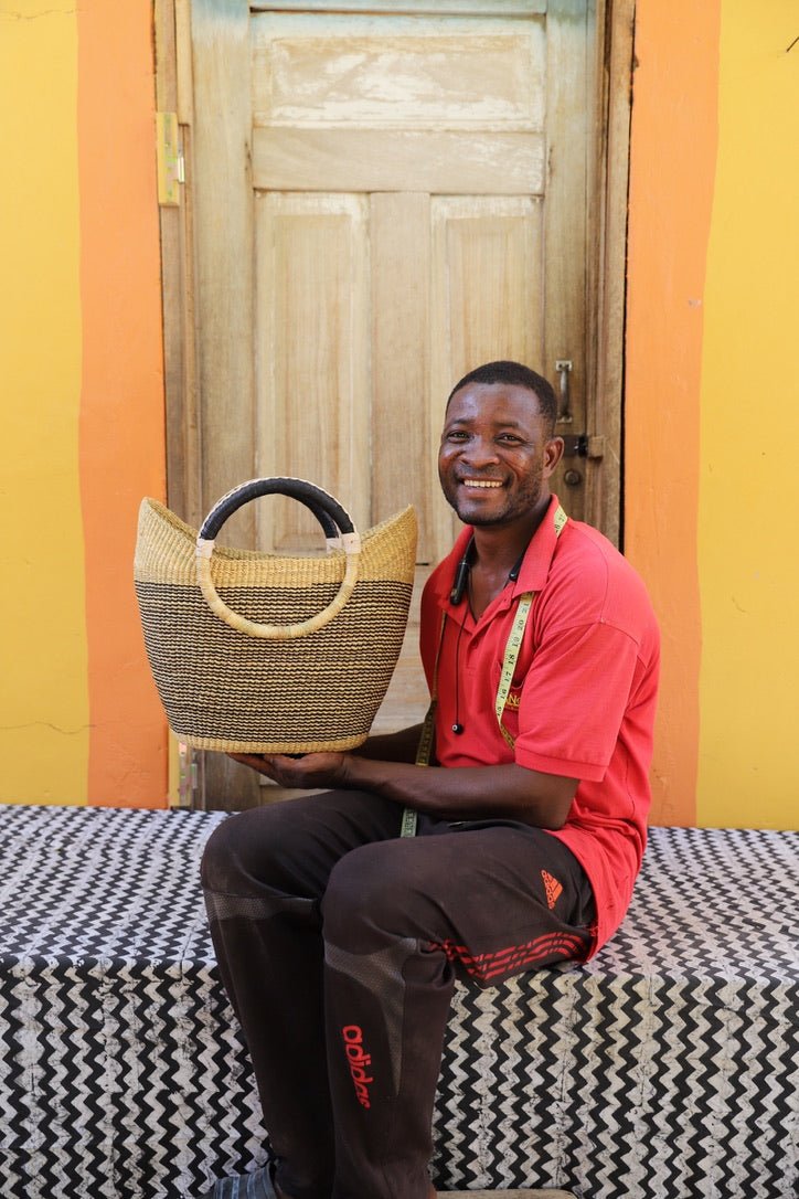 Man holding a woven basket in front of a colorful wall.