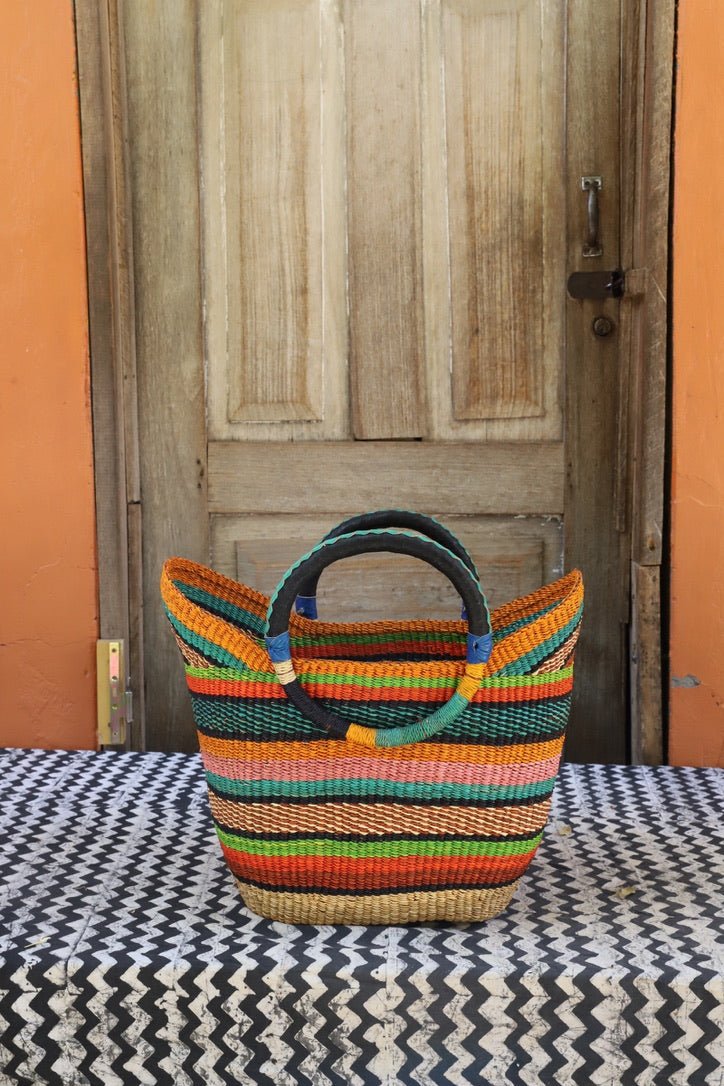 Woven carry on basket with premium leather on a black and white cloth against a wooden door