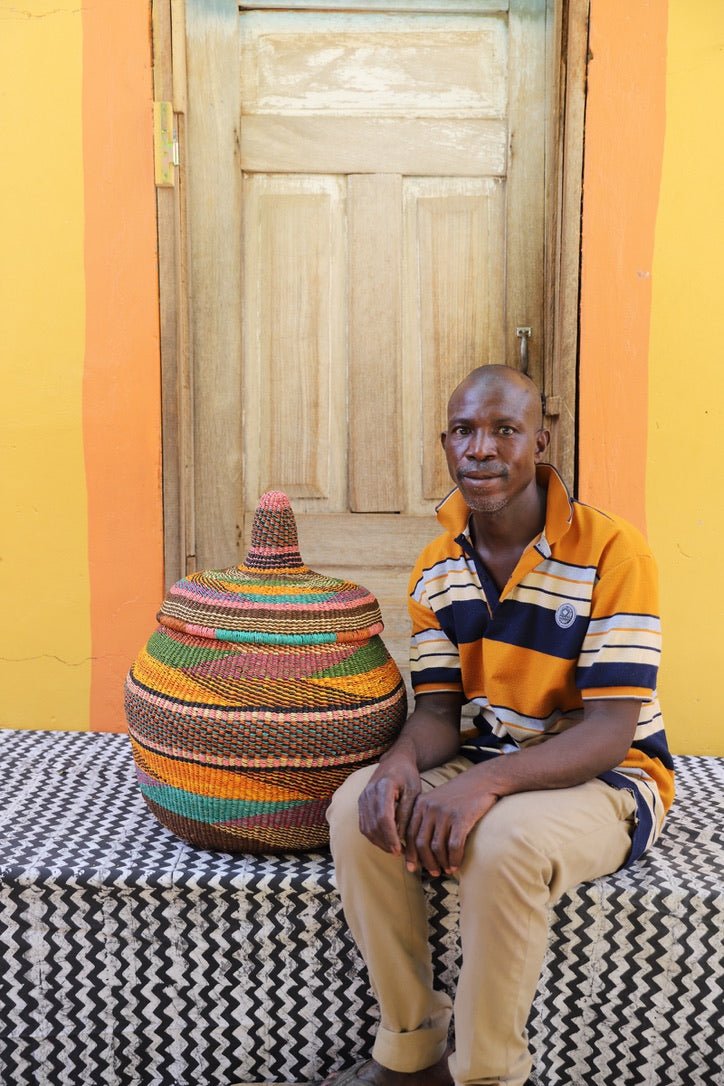 Man seated beside large Orbit storage basket in multicolour horizontal stripes, with lid