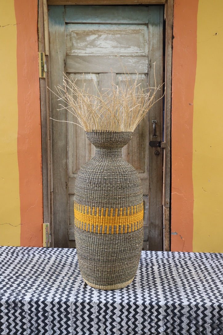 Decorative woven piece with stylish branches on a black and white cloth against a wooden door
