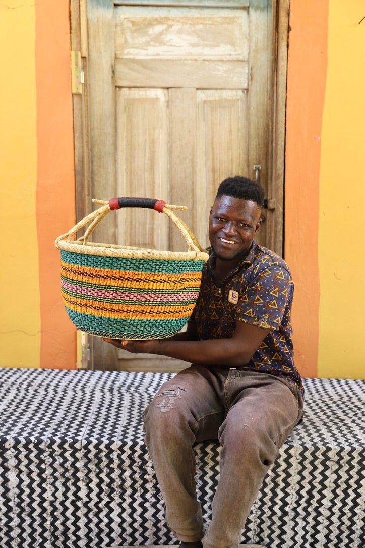 Man in patterned shirt holding a large teal, green and orange striped Bolga shopping basket