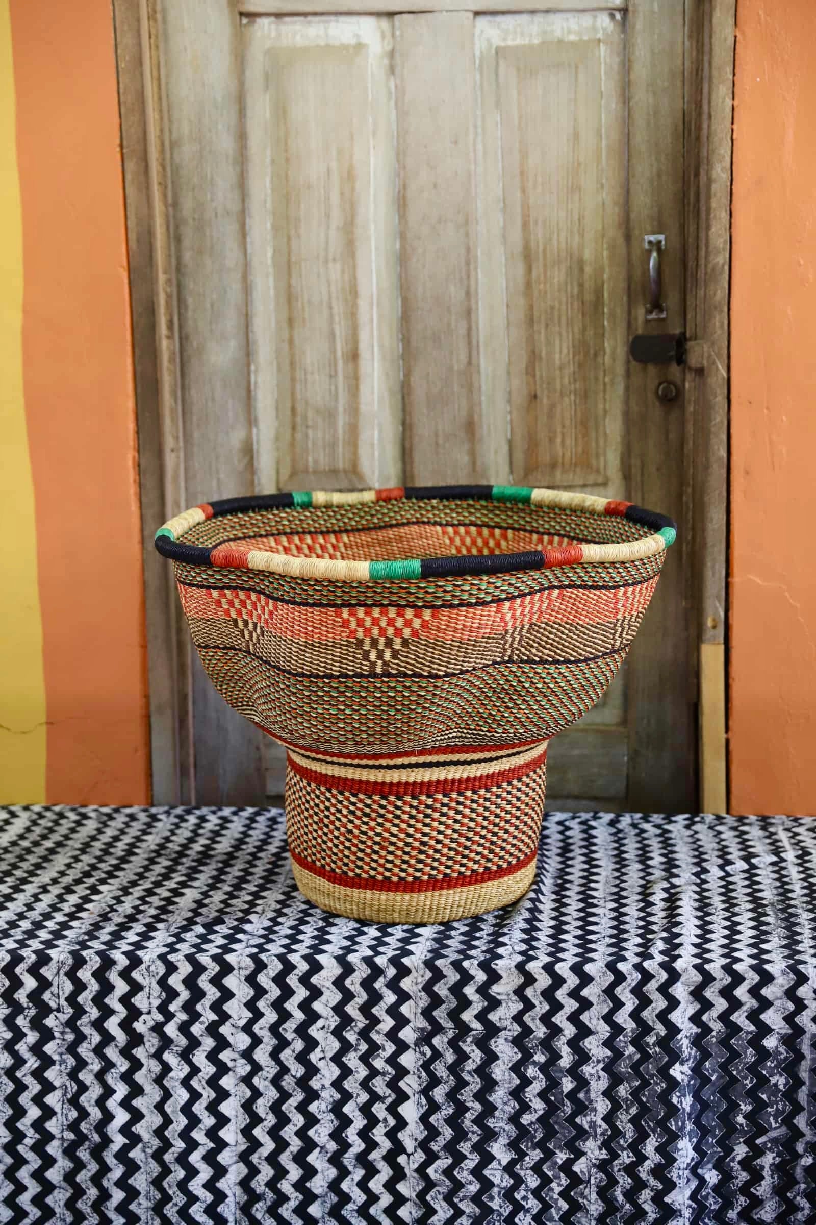 A colorful, handwoven piece sitting on a black and white cloth against a wooden door