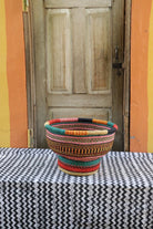 Colorful woven basket on a black and white patterned tablecloth with a wooden door in the background.